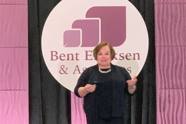 Lois Banta speaking on stage at a dental meeting